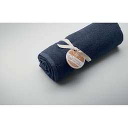 A rolled navy towel tied with a ribbon, featuring a tag with a logo and text.