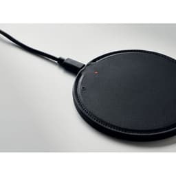 A black wireless charging pad with a slim, round design and a charging cable attached.