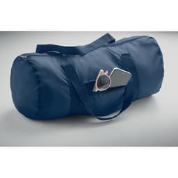 A navy duffle bag with a zip closure and two handles, featuring a pocket with sunglasses and a smartphone.