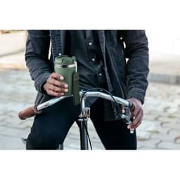 A drink bottle in olive green held by a person on a bicycle, with a logo visible on the bottle.