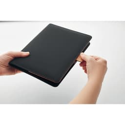 A black tablet case held by two hands, with a card being inserted into a slot. The case features a clean, sleek design.