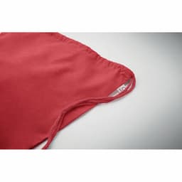 A red fabric product with a gathered edge and a strap, featuring a brand tag.