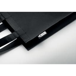 A black tote bag made of felt, featuring two handles and a small logo tag.