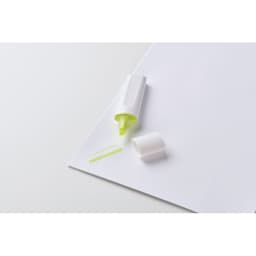 A highlighter pen in bright yellow with a white casing, placed on a sheet of white paper.