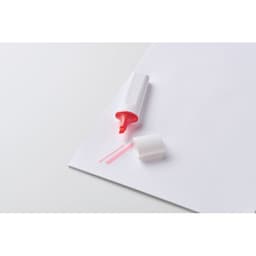 A pink highlighter on a white sheet of paper, with its cap removed and placed beside it.