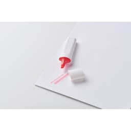 A highlighter with a pink ink tip lies on a sheet of white paper, cap off. It features a simple design.