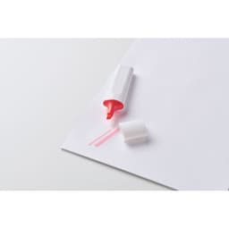 A pink highlighter with a white cap resting on a sheet of paper. The cap is off, revealing the bright tip.