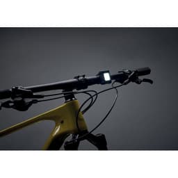 A bike handlebar with a yellow frame and a square light mounted on it, against a dark background.
