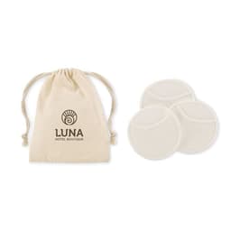 A drawstring bag in natural fabric, containing three round, white pads. The bag features a logo.