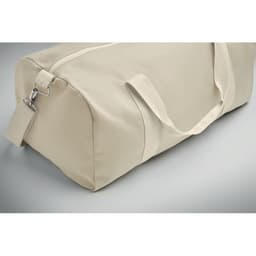 A beige duffle bag with a zip closure and adjustable shoulder strap, featuring sturdy handles.