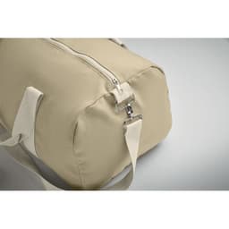 A tan duffel bag with a zippered closure and shoulder strap featuring a silver clip.
