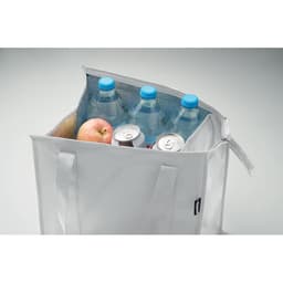A cooler bag containing three bottles of water, a can, and an apple, with light-coloured fabric and two handles.