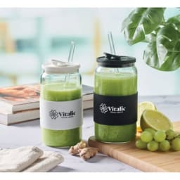 A drink bottle duo featuring green smoothies, with black and white sleeves, a black lid, and straws, on a kitchen countertop.