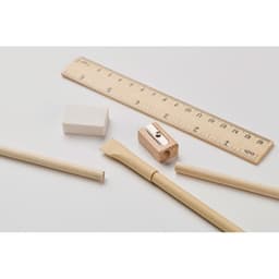 A wooden ruler, white eraser, sharpener, and pencil with a craft knife, all on a light background.