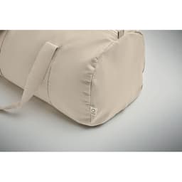 A beige duffle bag with a textured surface and a strap, featuring a small logo on the side.