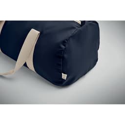 A dark blue duffle bag with cream straps and a small logo tag on the side.