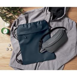 A navy drawstring bag, a grey pouch, and a grey hoodie are arranged on a wooden surface with decorative elements.