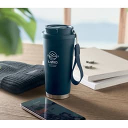 A drink bottle in navy blue with a handle, sitting on a table beside a phone and a beanie. It has a logo.
