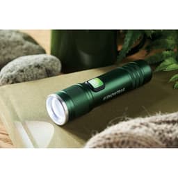 A green flashlight with a textured body, silver light bezel, and a power button, placed on a textured surface.