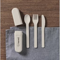 A portable cutlery set in light grey, including a spoon, fork, knife, and storage case, laid on a blue cloth.