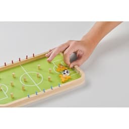 A tabletop soccer game with a green field and wooden player figures, showing a hand moving a player.