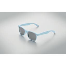 Light blue sunglasses with dark lenses, resting on a smooth, reflective surface. The design features a sleek, modern style.