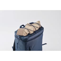 A navy backpack with a tan item secured on top by elastic cords. The bag features a zippered compartment.