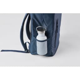 A drink bottle is nestled in a mesh pocket of a navy backpack, featuring a silver lid.