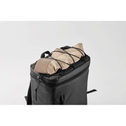 A black backpack featuring a top compartment secured with elastic straps, holding beige items.