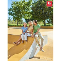 A green men's tubular cotton T-shirt worn by a man sitting with two women in a sunny skate park.