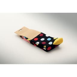 A pair of black socks featuring colourful polka dots, with a yellow toe, packaged on a cardboard backing.
