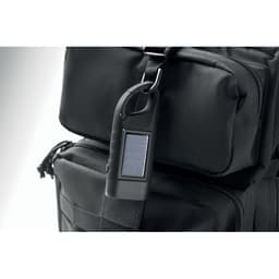 A black backpack with a solar-powered charger attached to the strap. The design is sleek and utilitarian.