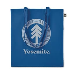 A blue tote bag featuring a circular graphic with a tree design and the word "Yosemite." It has two shoulder straps.
