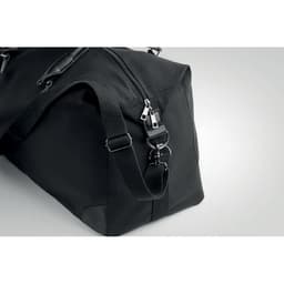 A black duffel bag featuring a zip closure and adjustable strap, with metal clasps and detailing.