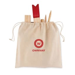 A drawstring bag in beige containing wooden utensils and a red spatula, featuring a logo on the front.
