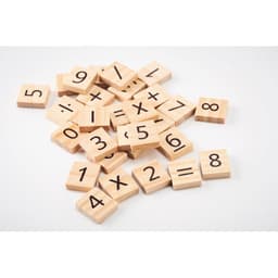 A collection of wooden tiles with numbers and mathematical symbols in natural wood colour scattered on a surface.