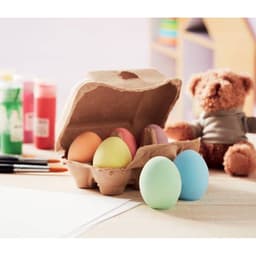 A drink bottle in pastel colours placed beside an egg carton filled with painted eggs, surrounded by craft supplies and a teddy bear.