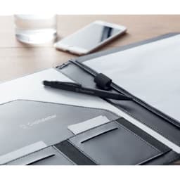 A black pen rests on a grey folder, with a glass of water and a smartphone in the background. The folder includes card slots.