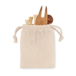 A drawstring bag in natural fabric containing wooden utensils and a round wooden serving piece.