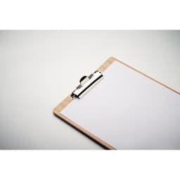 A clipboard with a wooden backing and a silver clip holds a blank sheet of white paper.