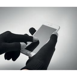 A pair of black gloves with grey fingertips is shown, actively using a smartphone screen.