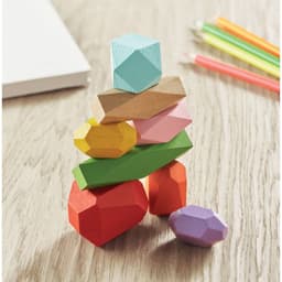 A stack of colourful wooden shapes in various geometric forms, including red, green, pink, yellow, blue, and natural wood.