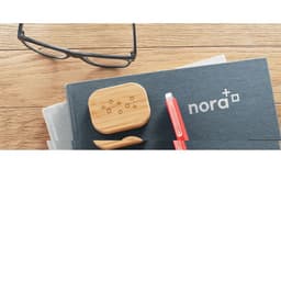A wooden accessory case and a pen in red, placed on a dark grey notebook, with eyeglasses nearby.