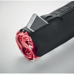 A rolled-up blanket in a black carrying bag with a phone partially visible in the zippered pocket.