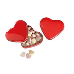 A heart-shaped red tin containing pastel-coloured heart-shaped sweets, with a few sweets outside the tin.