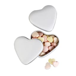 A heart-shaped tin containing pastel-coloured heart-shaped sweets, with some sweets scattered outside the tin.