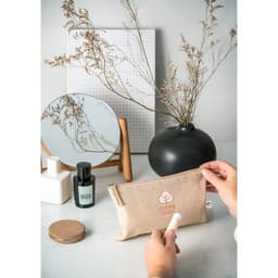 A beige multifunction bag made from recycled cotton and polyester, placed on a minimalist table with decorative items.