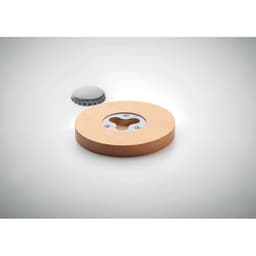 A bottle opener with a wooden base and a metallic upper part, featuring a circular design and a bottle cap beside it.