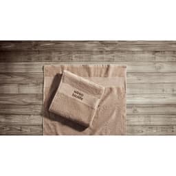 A set of beige towels featuring a folded towel on top of a larger one, both displayed on a wooden surface.
