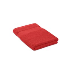 A red bath towel neatly folded, featuring a textured surface and a smooth band along the edge.